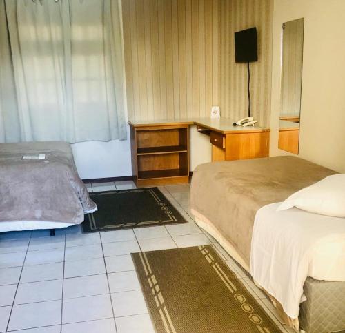 a bedroom with two beds and a desk and a television at Villa Apart Hotel in Lages