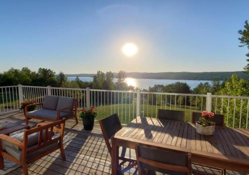 a deck with a table and chairs and a view of the water at Au Sommet du Lac Magog in Magog-Orford