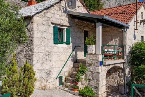 a stone house with a green window and stairs at stone house Nikolina with heated Pool in Bast