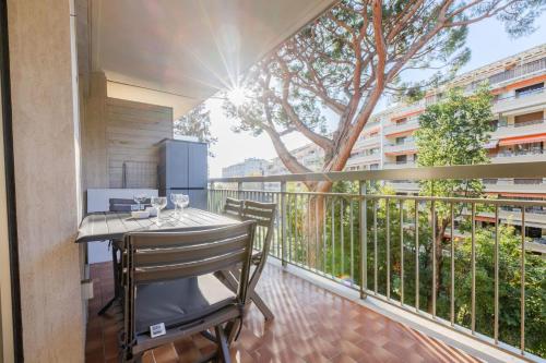 d'un balcon avec une table, des chaises et un arbre. dans l'établissement Renovated 3-Room Apartment in a Leafy Park, à Cannes