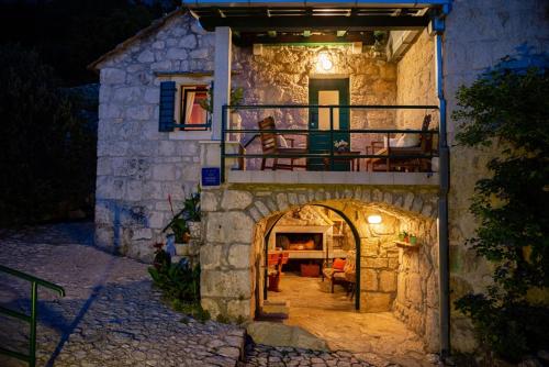 a stone house with a balcony and a patio at stone house Nikolina with heated Pool in Bast