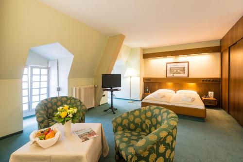 a hotel room with a bed and two chairs at Schlosshotel Weilburg in Weilburg
