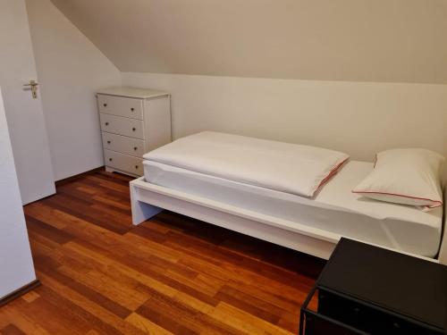 ein kleines Schlafzimmer mit einem weißen Bett und einer Kommode in der Unterkunft Appartment Himmelblau in Friedrichshafen