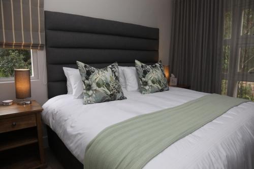 a bedroom with a large white bed with two pillows at Sunbird Bliss Luxury Self-catering Apartment in Wilderness