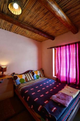 a small bedroom with a bed with a window at Tilcara Rustica Hostel in Tilcara