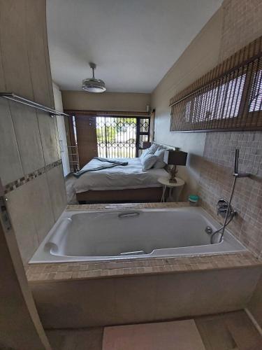 a bath tub in a bedroom with a bed at Whale Rock, Modern Beachfront Apartment in Margate