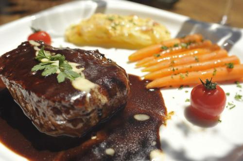 a plate of food with meat and carrots and sauce at Adler Botenheim in Botenheim