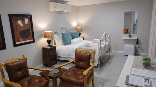 a bedroom with a bed and two chairs and a table at Gazelle Estate in Kakamas