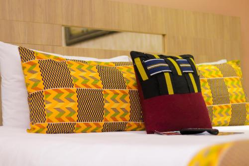 a bed with colorful pillows on top of it at Bays Lodge, Accra in Accra