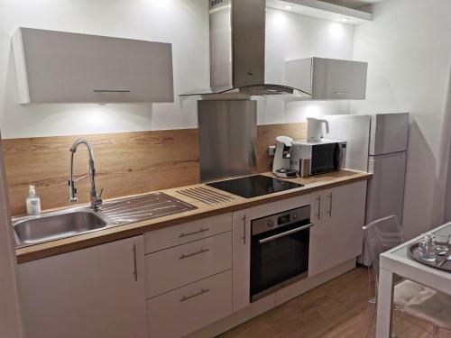 cocina con fregadero y microondas en Front de mer- Appartement standing 1 chambre en Calais