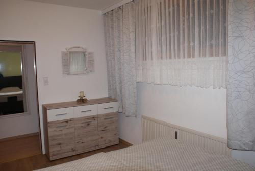 a bedroom with a dresser and a window with a mirror at Apartman BKK in Bad Kleinkirchheim