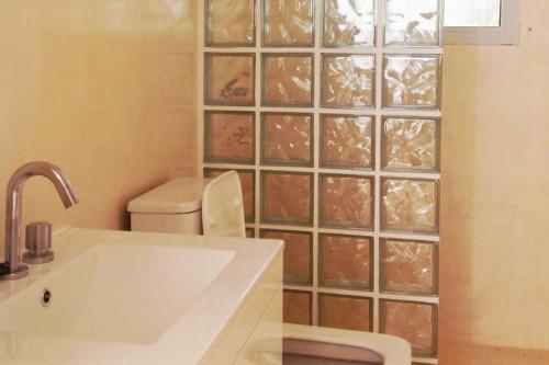 baño con lavabo, aseo y pared de cristal en Private guesthouse & pool en Los Cocos