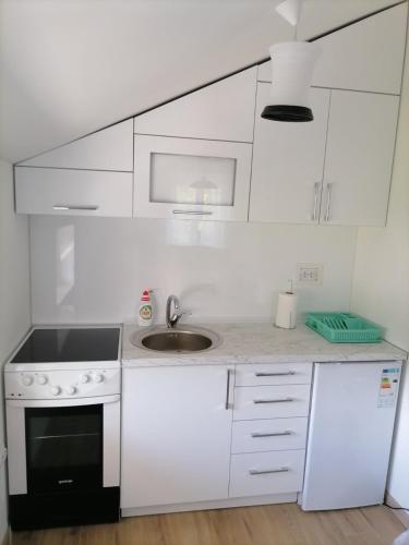 a white kitchen with a sink and a stove at Drobnjak apartments in Bijelo Polje