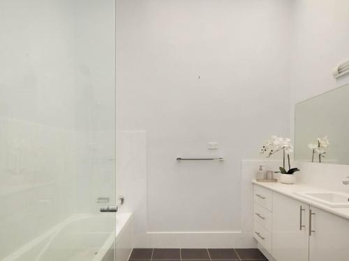 een witte badkamer met een douche en een wastafel bij The Muse At Gerringong in Gerringong