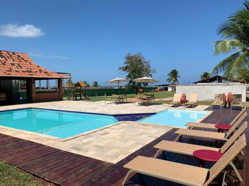 uma piscina com cadeiras e um deque com uma casa em Catamaran Praia Chalés em Igarassu