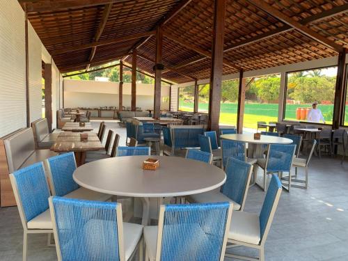 um restaurante com mesas e cadeiras e pessoas ao fundo em Catamaran Praia Chalés em Igarassu