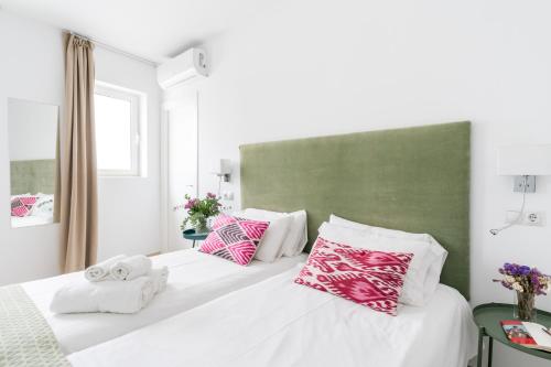 1 dormitorio con 2 camas y almohadas rosas y blancas en Apartamentos RG Suites Plaza del Salvador, en Sevilla