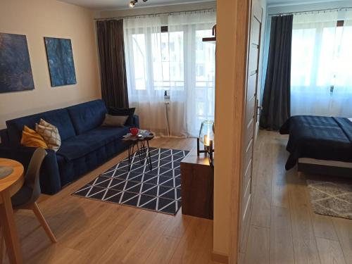 ein Wohnzimmer mit einem blauen Sofa und einem Tisch in der Unterkunft MD Apartament Lewandowskiego in Stettin