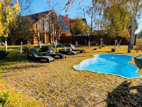 a row of chairs and a swimming pool in a yard at Домик с баней на озере Мартышев in Kyiv