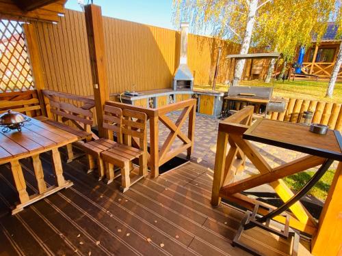 a patio with wooden tables and chairs and a grill at Домик с баней на озере Мартышев in Kyiv