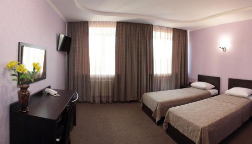 a hotel room with two beds and a desk at Kristall Hotel in Surgut