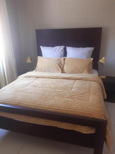 a bed with a black headboard and white sheets and pillows at Halina's Apartment in Lusaka