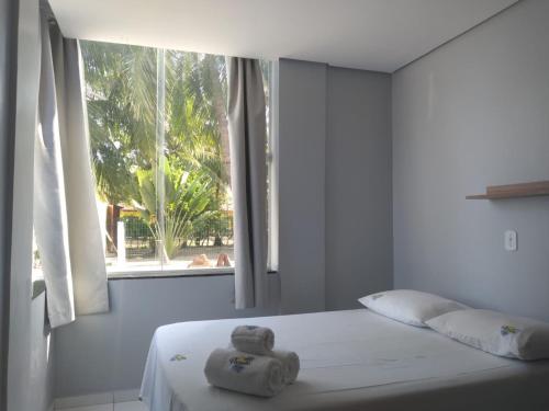 a white bedroom with a bed with a window at Paraiso do Sul Maragogi in Maragogi