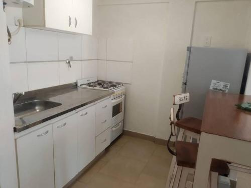 - une cuisine blanche avec évier et cuisinière dans l'établissement Departamento Albarracin, à San Carlos de Bariloche