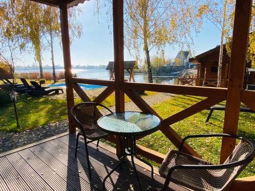 a table and chairs on a deck with a view of the water at Домик у озера с мангалом и террасой in Kyiv