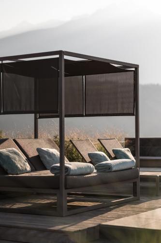 a bed with pillows and an umbrella on a deck at Hotel Das Dorner in Lagundo