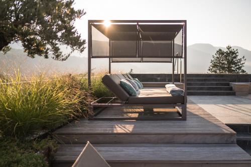 a couch sitting on a deck with a canopy at Hotel Das Dorner in Lagundo