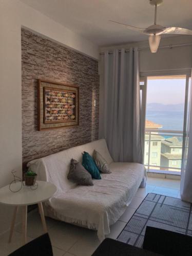 a living room with a couch and a large window at Porto Real Suites Resort in Mangaratiba