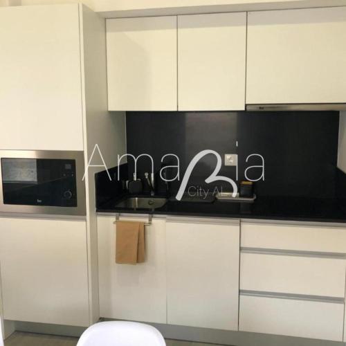 a kitchen with white cabinets and a black counter top at AmaRiaCity AL in Aveiro