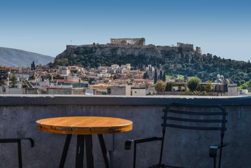 a table and chairs on a ledge with a view ofhens at A.P. Acropolis View Apartments in Athens