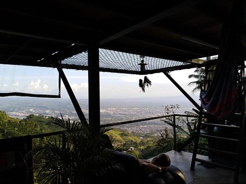 a person laying on a balcony with a view of the city at Glamping Casa Viva in Pereira