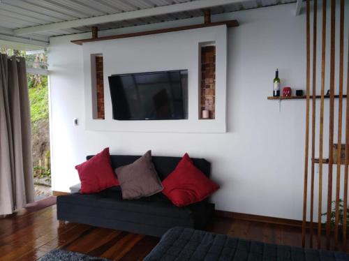 sala de estar con sofá y TV en la pared en Glamping Casa Viva, en Pereira