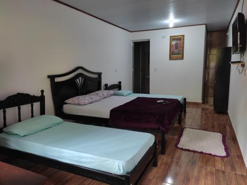 三一市的住宿－Pousada Sossego da Vila - Trindade Paraty，铺有木地板的客房内的两张床