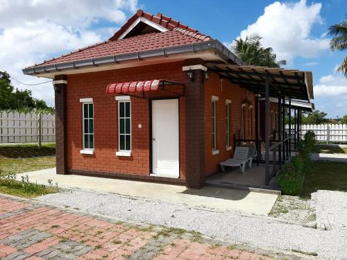 a small red brick house with a white door at GekQ Inn Langkawi B in Pantai Cenang