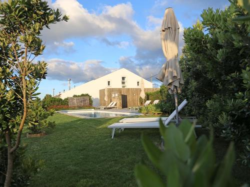 a umbrella sitting in a yard next to a pool at Antiga Fábrica de Chá in Nordestinho
