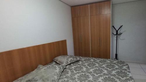 a bedroom with a bed and a wooden cabinet at Apto confortável Grand Reserva Casa da Madeira! in Caldas Novas