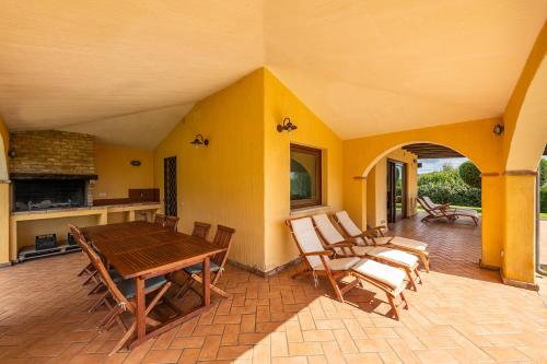 un gran patio con mesa de madera y sillas en Villa Anna Maria, en Villasimius