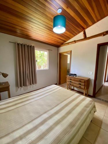 Casa em Área Rural - Delfinópolis في ديلفينوبوليس: غرفة نوم بسرير كبير وسقف خشبي