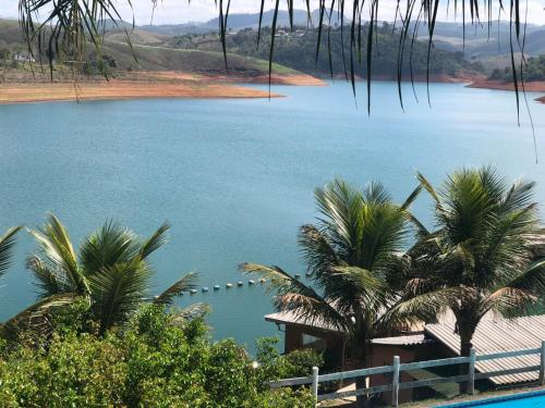 a view of a lake with palm trees and a house at Chalé das Águas in Igaratá