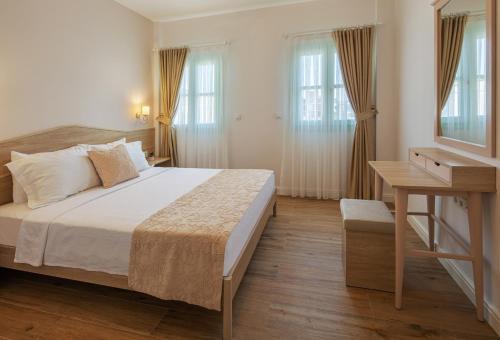 a bedroom with a bed and a desk and windows at Çiğdem'inn Sığacık (Cigdeminn Sigacik) in Siğacık