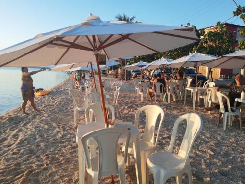 a group of chairs and an umbrella on the beach at RESONAMUH - Hostel in São Pedro da Aldeia