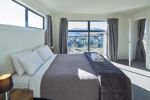 ein Schlafzimmer mit einem Bett und einem großen Fenster in der Unterkunft Alpine View Apartment 3 - Tekapo in Lake Tekapo