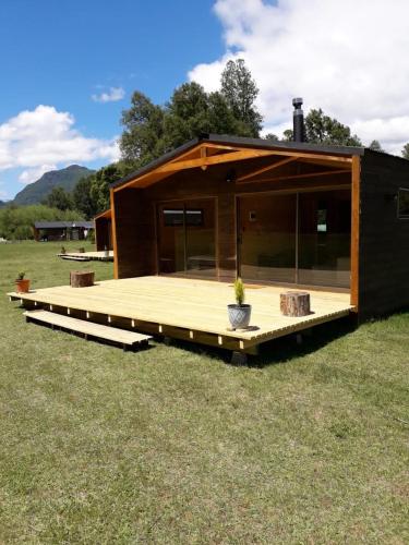 a small cabin with a deck in a field at Parque Relicura in Palguín