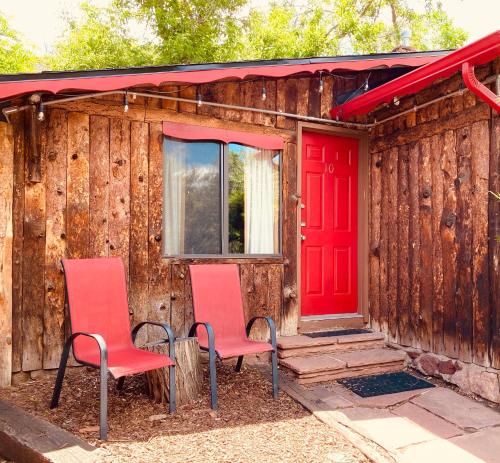 zwei Stühle vor einem Haus mit roter Tür in der Unterkunft Foot of the Mountain Motel in Boulder