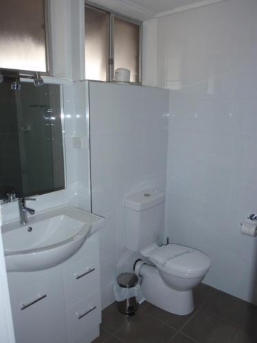 a white bathroom with a toilet and a sink at Mid City Plantation Motel in Mildura