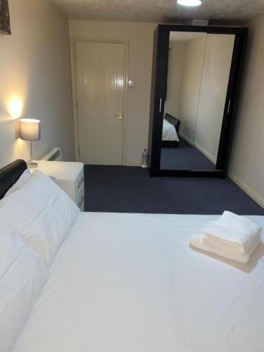 a bedroom with a large white bed and a mirror at Service Apartment in Thamesmead